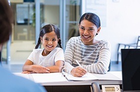 Smiling mother and daughter at reception desk