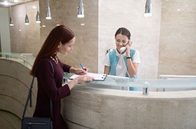 Patient signing papers at dental office front desk