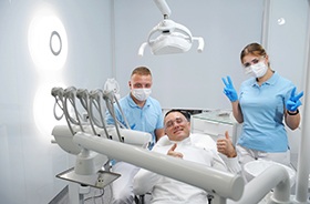 Happy patient posing with dental team