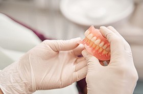 Gloved hands holding set of dentures