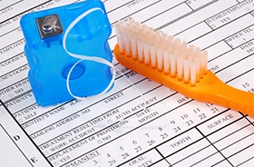Floss and toothbrush sitting on top of dental insurance form