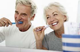 Couple brushing their teeth to prevent dental emergencies in Hamden