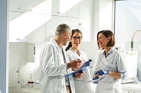 Happy dental team members holding clipboards