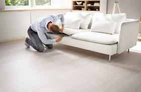 Man searching under couch cushions for lost item