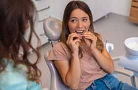 Dental patient placing clear aligner in her mouth