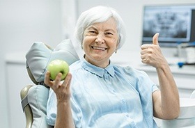 Older woman in dental chair giving thumbs