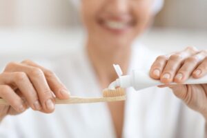 Woman in white bathrobe preparing to brush her teeth