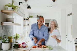 Older couple happily preparing a meal in kitchen